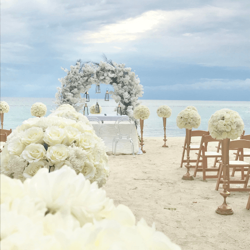 altar on a beach with flowers and chairs for the guests